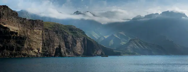 Playa de las Nieves beach in Gran Canaria, featuring a pebbly shoreline with moderate water conditions, certified with Blue Flag status for environmental quality