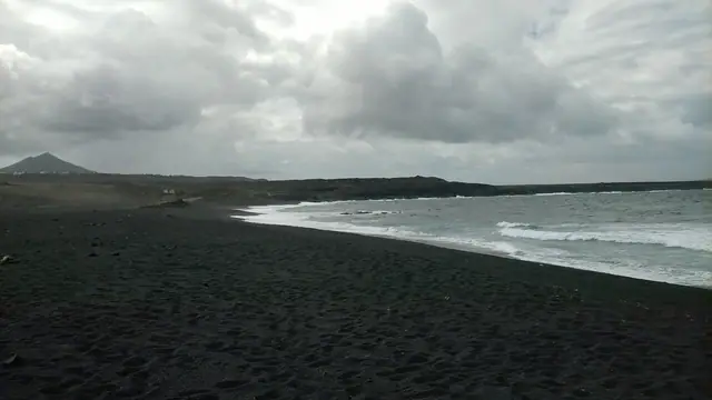 Playa de Janubio beach in Lanzarote, featuring a sandy shoreline with moderate water conditions