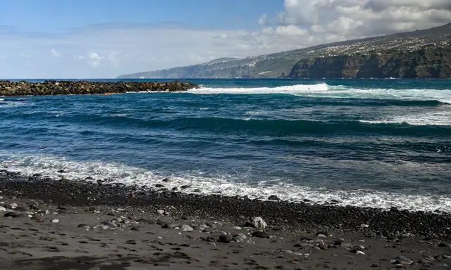 Playa Martiánez beach in Tenerife, featuring a sandy shoreline with calm water conditions