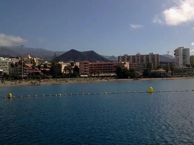 Playa de Los Cristianos beach in Tenerife, featuring a sandy shoreline with calm water conditions