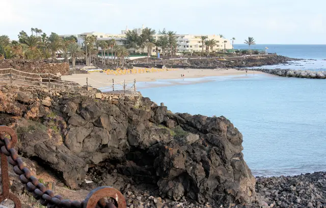 Playa Flamingo beach in Lanzarote, featuring a sandy shoreline with calm water conditions