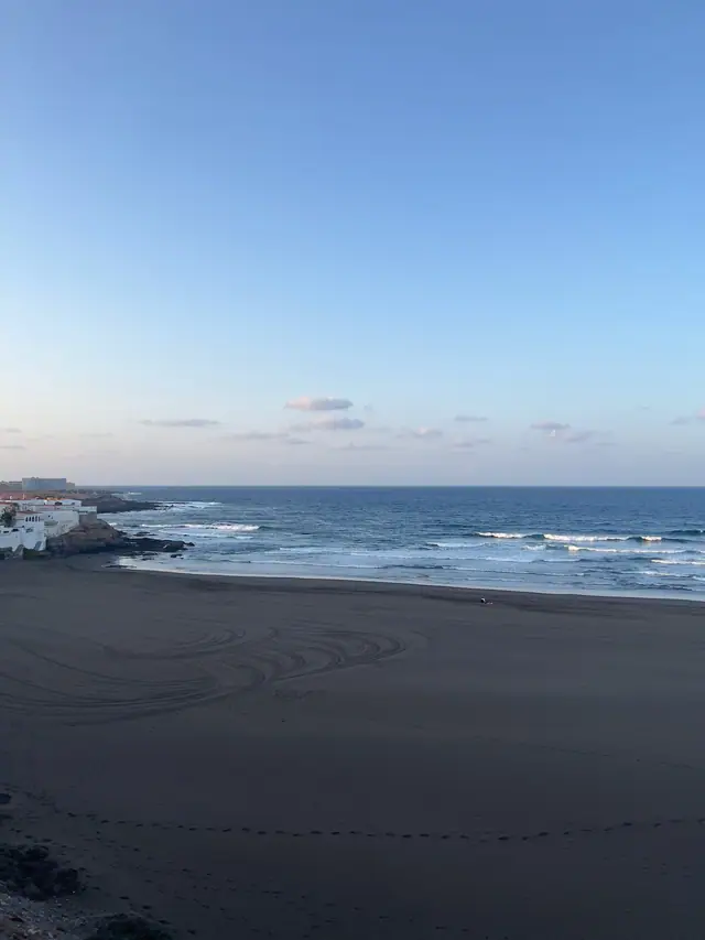 Playa del Hombre beach in Gran Canaria, featuring a sandy shoreline with surfable water conditions