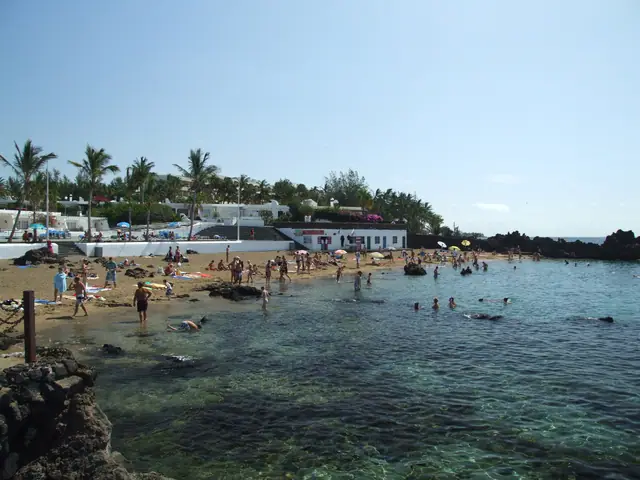 Playa Pila de la Barrilla (Playa Chica) beach in Lanzarote, featuring a sandy shoreline with wavy water conditions, certified with Blue Flag status for environmental quality