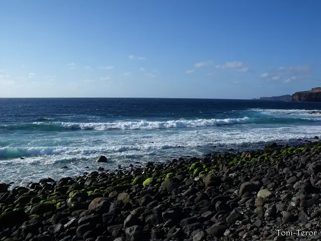 Playa Las Salinas beach in Gran Canaria, featuring a pebbly shoreline with calm water conditions