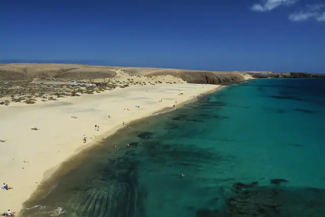 Playa Mujeres beach in Lanzarote, featuring a sandy shoreline with moderate water conditions