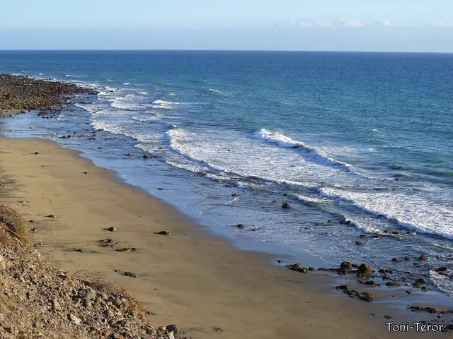 Playa de las mujeres beach in Gran Canaria, featuring a pebbly shoreline with calm water conditions