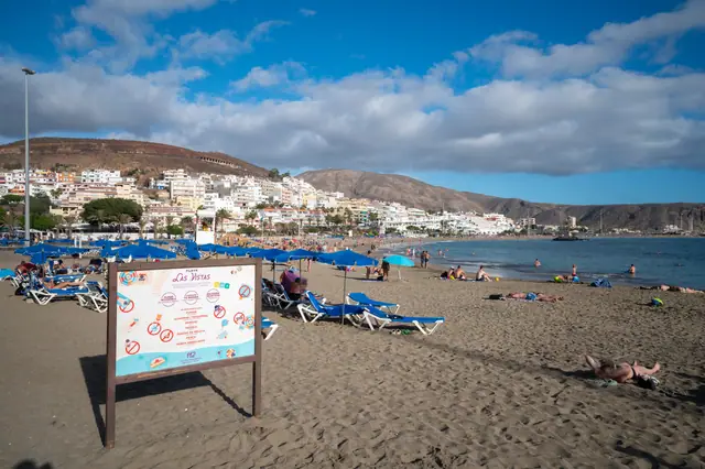 Playa de Las Vistas beach in Tenerife, featuring a sandy shoreline with calm water conditions, certified with Blue Flag status for environmental quality