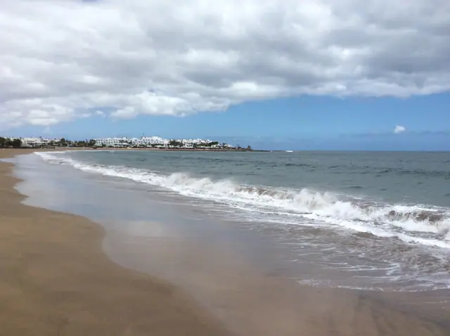 Playa de los Pocillos beach in Lanzarote, featuring a sandy shoreline with calm water conditions