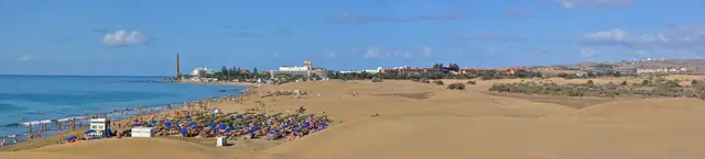 Playa de Maspalomas beach in Gran Canaria, featuring a sandy shoreline with calm water conditions, certified with Blue Flag status for environmental quality