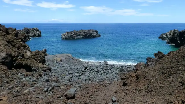 Los Puentes beach in El Hierro, featuring a pebbly shoreline with wavy water conditions
