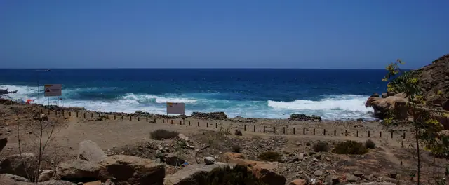 Playa Medio Almud beach in Gran Canaria, featuring a pebbly shoreline with moderate water conditions