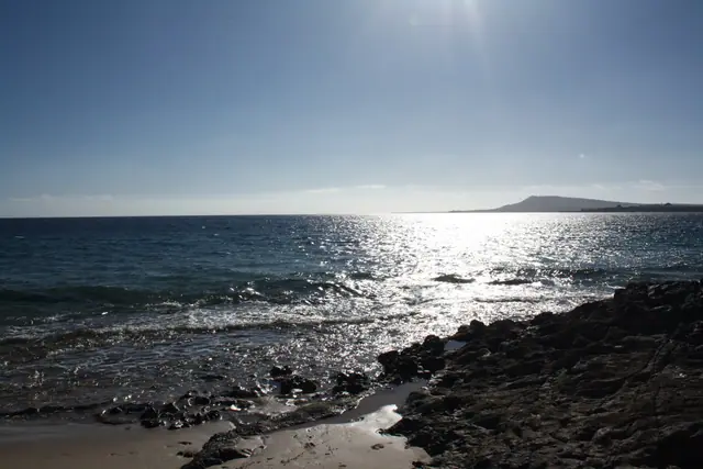 Playa de Puerto Muelas beach in Lanzarote, featuring a sandy shoreline with wavy water conditions