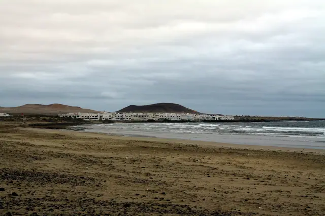 Playa de Famara beach in Lanzarote, featuring a sandy shoreline with surfable water conditions