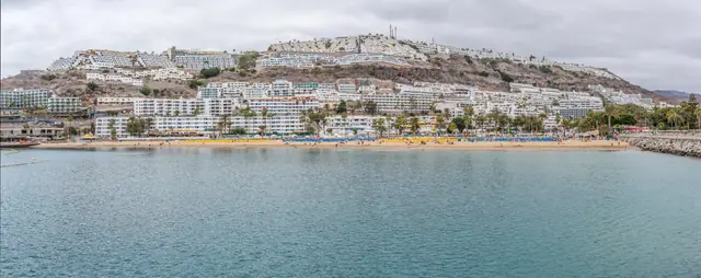 Playa de Puerto Rico beach in Gran Canaria, featuring a sandy shoreline with calm water conditions