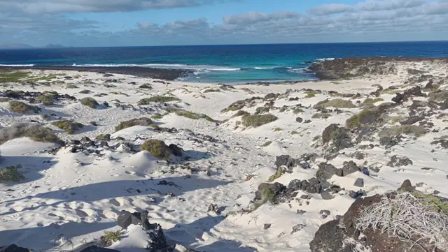Caleta del Mojon Blanco beach in Lanzarote, featuring a sandy shoreline with moderate water conditions