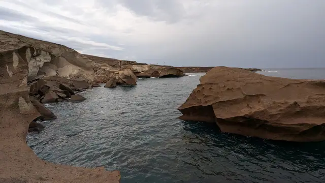 Playa Tajao beach in Tenerife, featuring a pebbly shoreline with calm water conditions